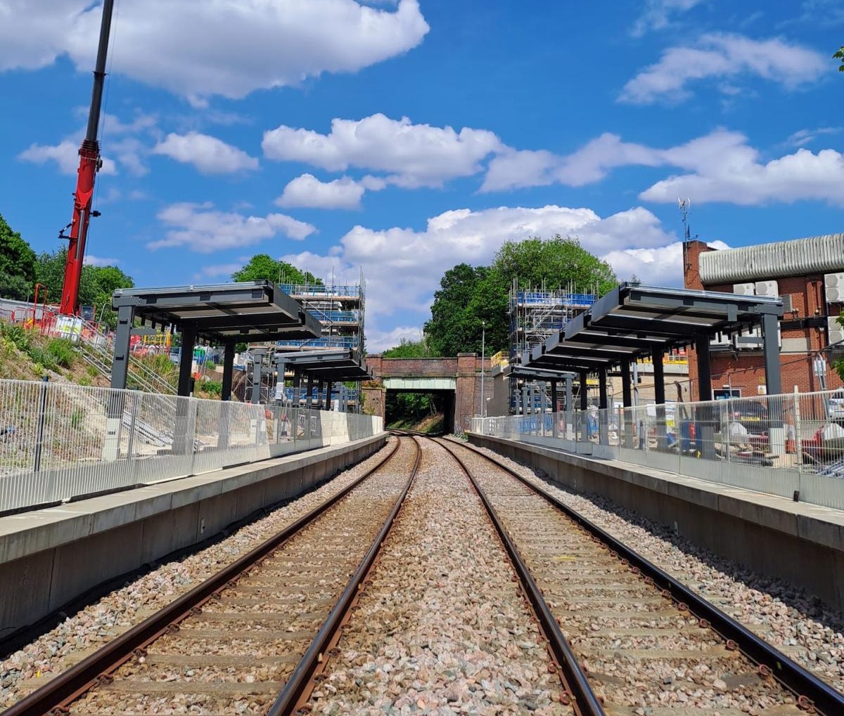 Railway track flanked by platforms showing the new canopies installed. It's a cloudy day.
